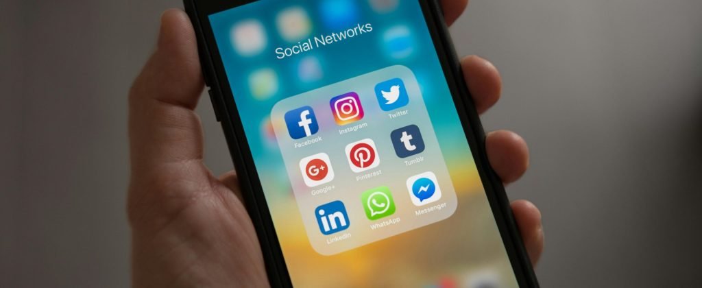 Person Holding Iphone Showing Social Networks Folder